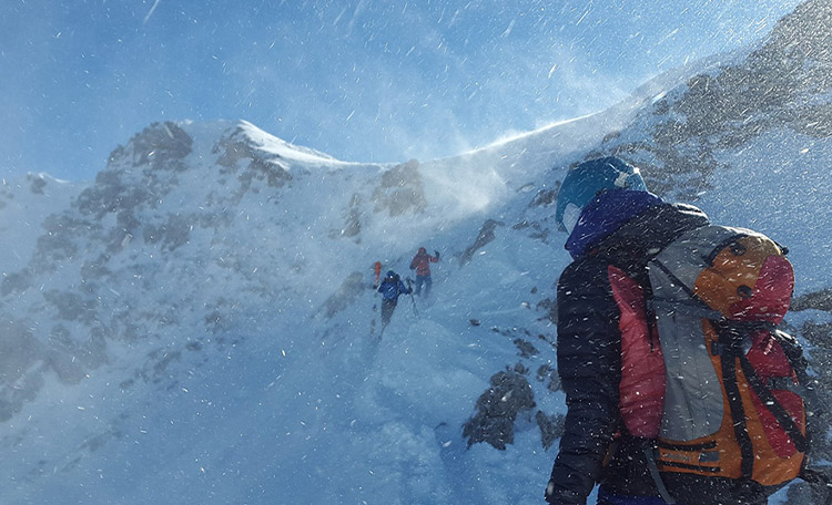 Sterke wind tijdens skitochten kan niet alleen onaangenaam zijn, maar ook echt gevaarlijk. Skitourganger in harde wind op een berghelling