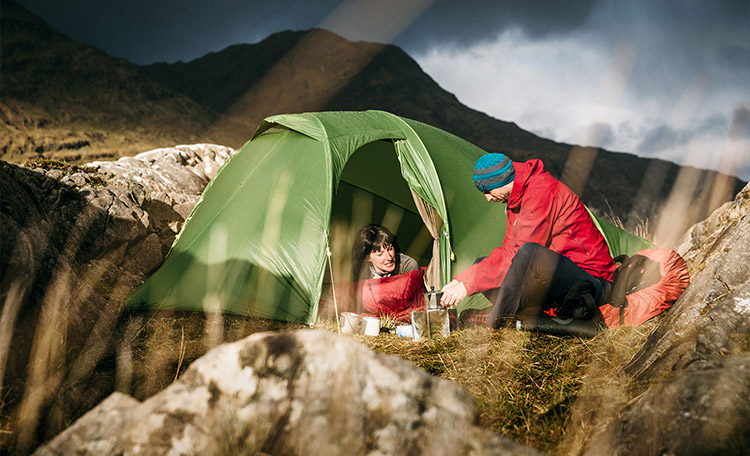 Waterkolom voor de tentbodem Man en vrouw zitten bij zonnig weer in een tent en lachen naar elkaar